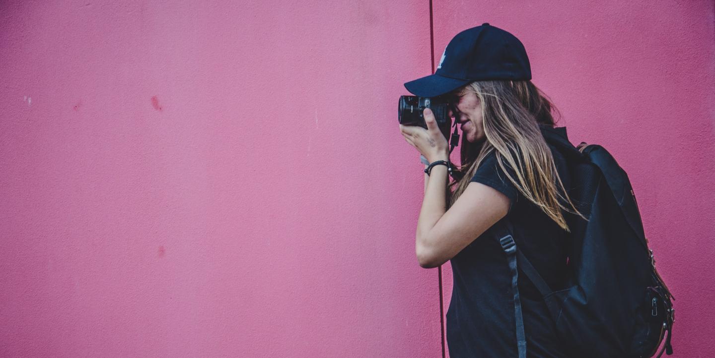 Fotógrafa em frente a uma parede rosa