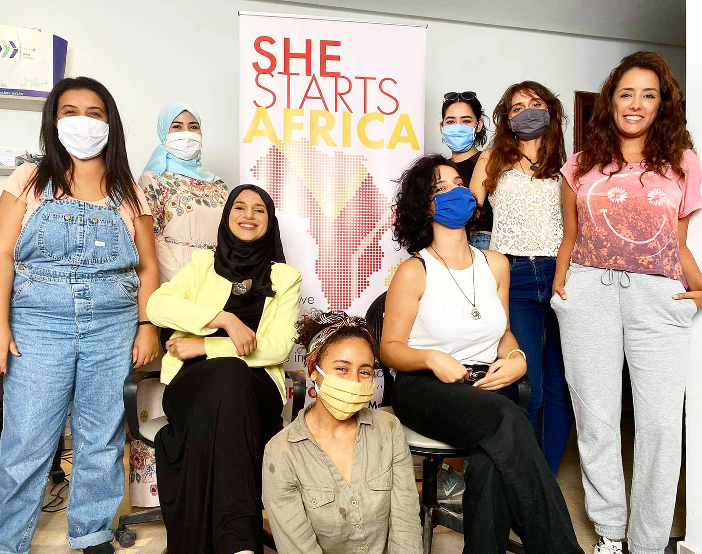 A group of women standing around a sign that says "she starts Africa"