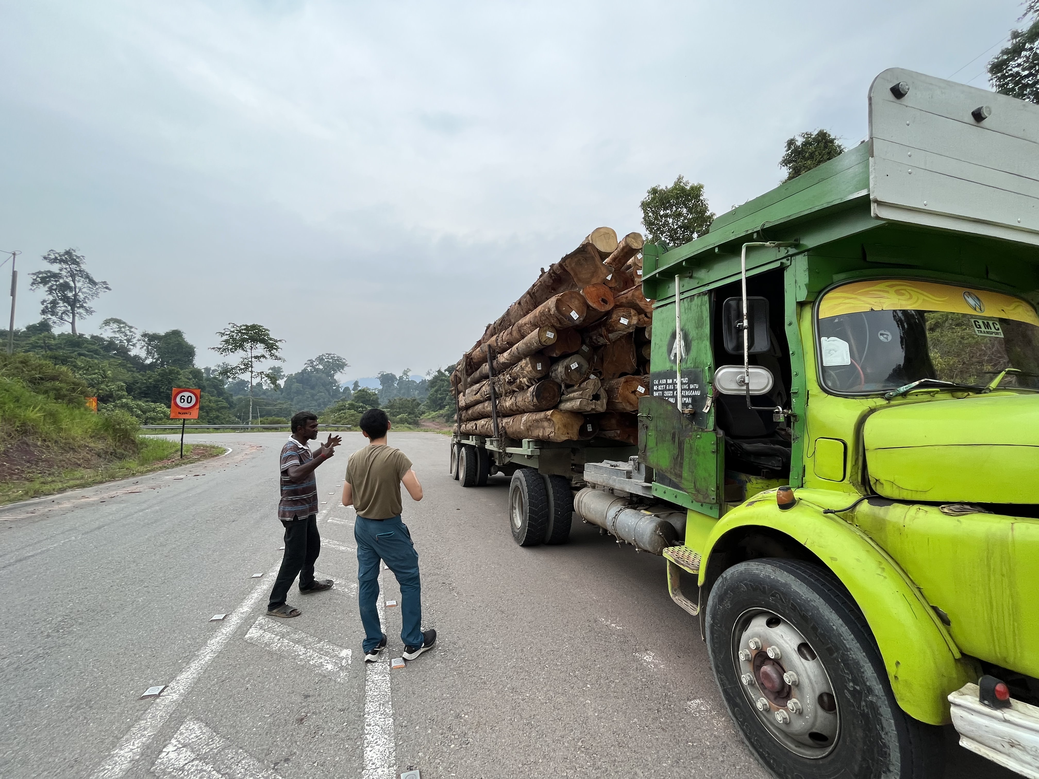 Chyuan talking to a truck driver, who is transporting logs.