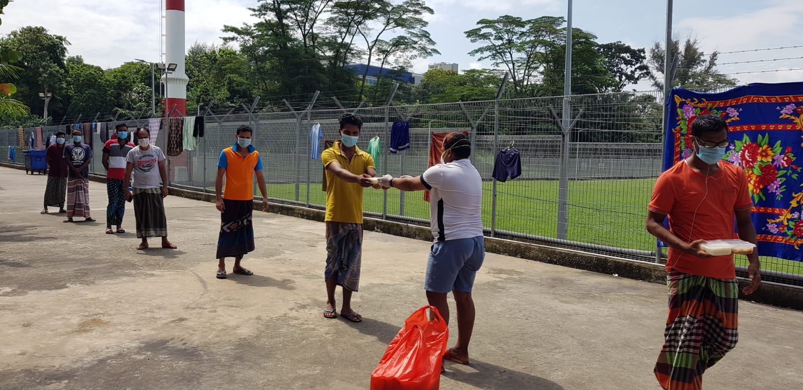 Migrant workers living in dorms line up to receive food