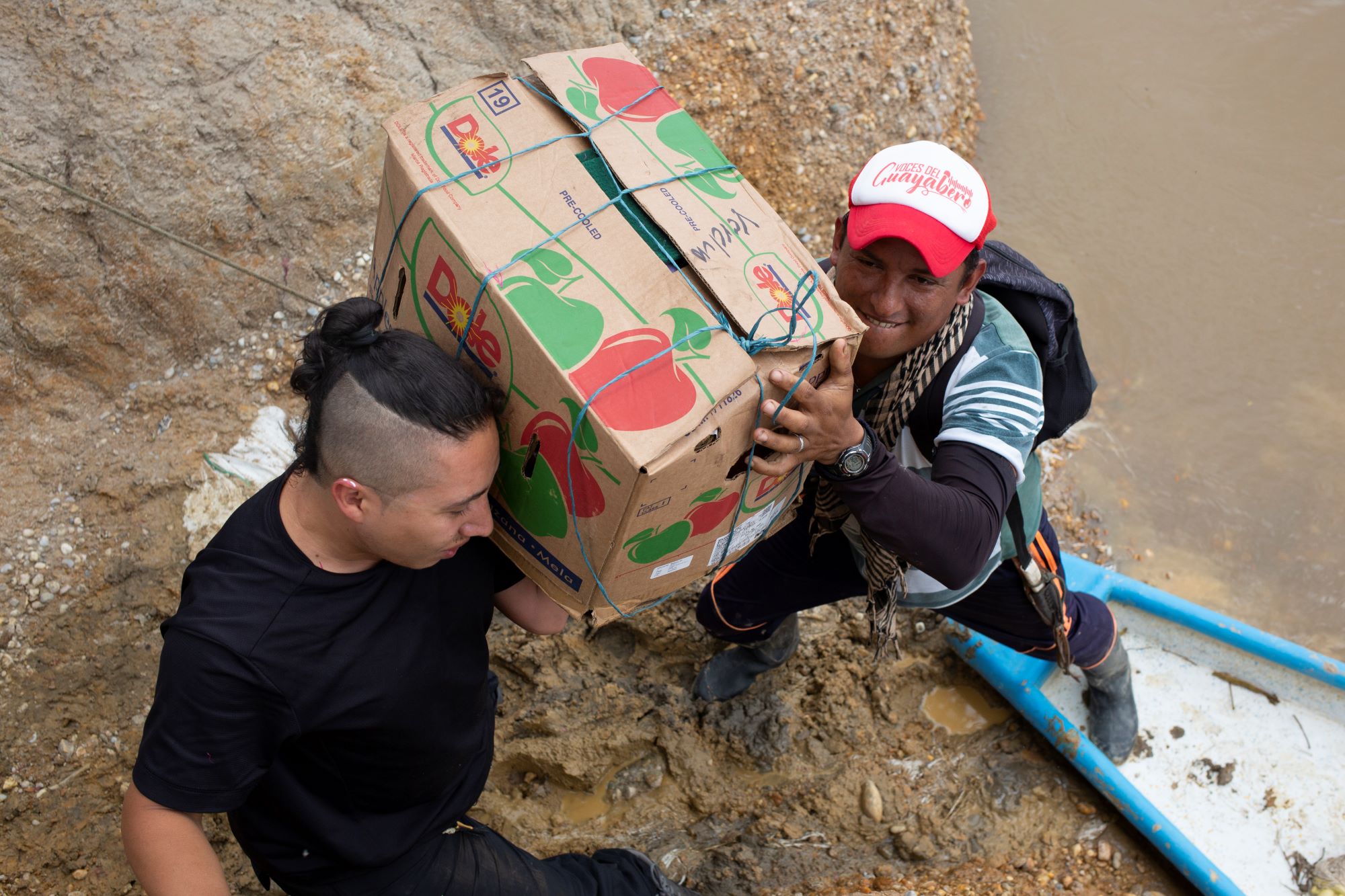 Vladimir Encina, a photojournalist from El Cuarto Mosquetero, and Voces Del Guayabero reporter Edilson Álvarez, right, load donations into a boat bound for Nuevo Colombia on May 25, 2023.