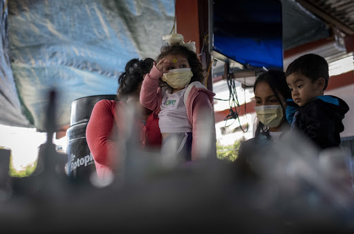 Migrant parents and children at a migrant shelter in Tijuana, Mexico, wear surgical masks to protect against contracting COVID-19 (credit: Christian Monterrosa).  