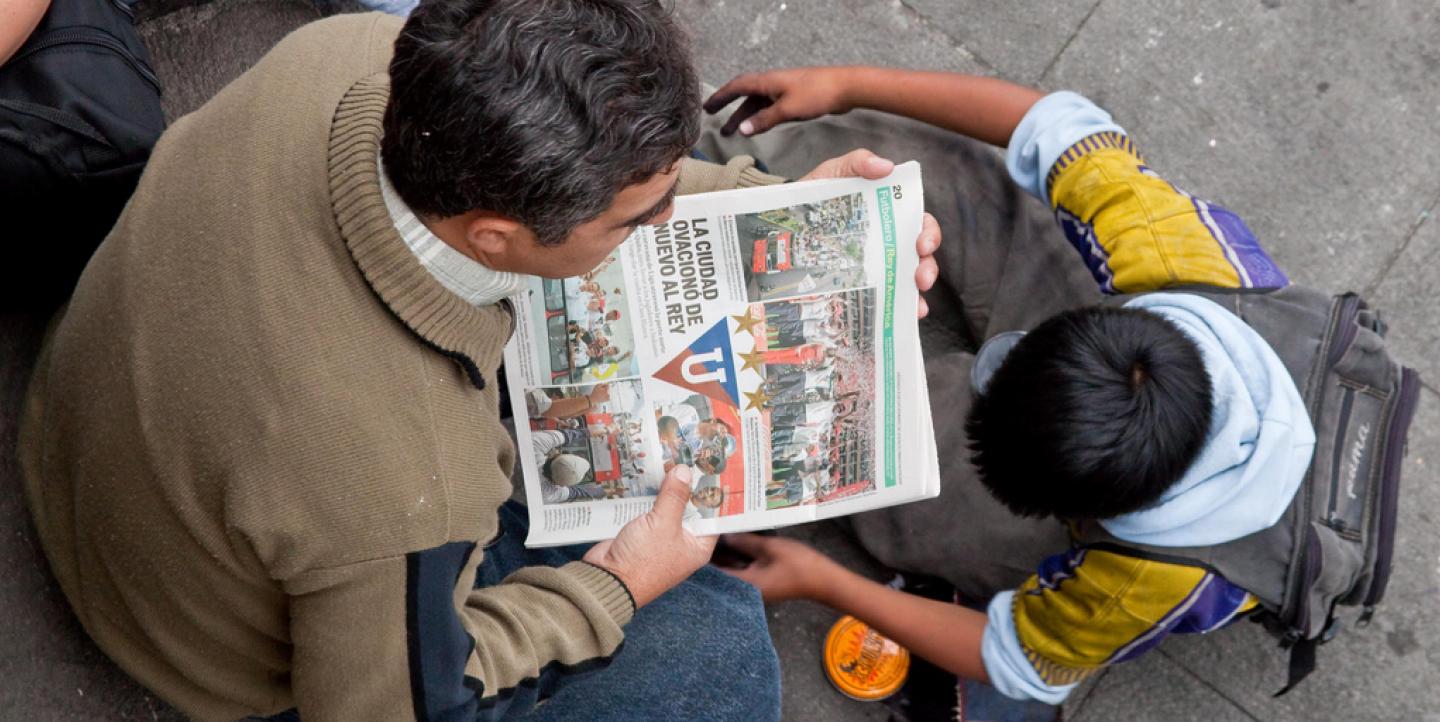 Man and child look at newspaper
