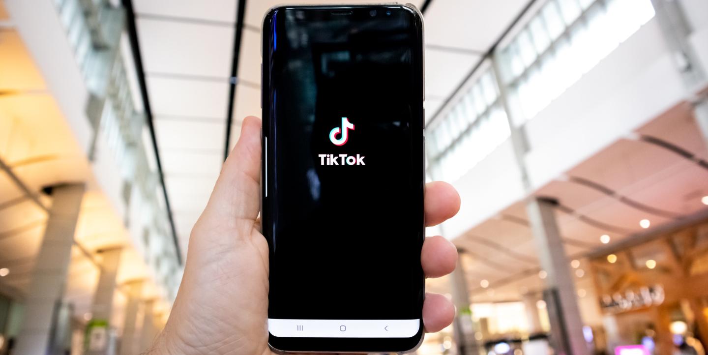 Hand holding a phone with TikTok logo