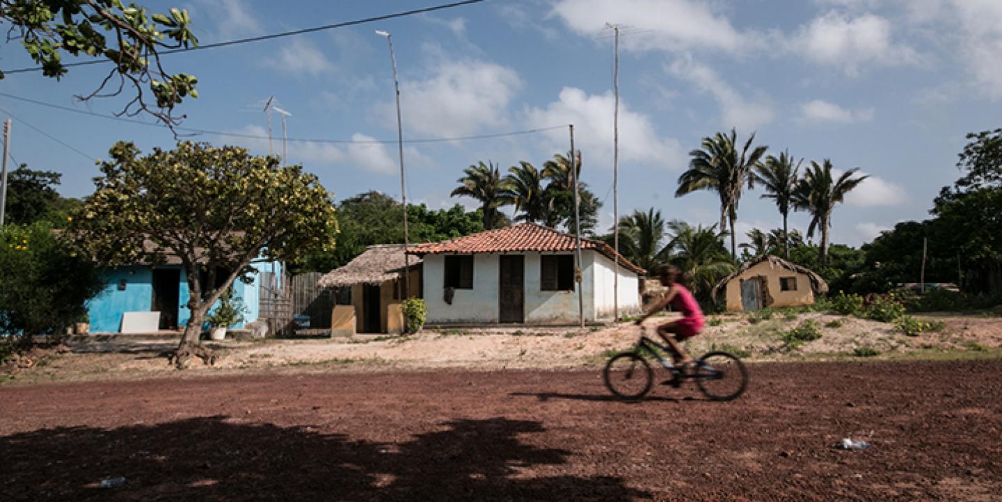 Rapaz andando de bicicleta em rua de terra na comunidade quilombola