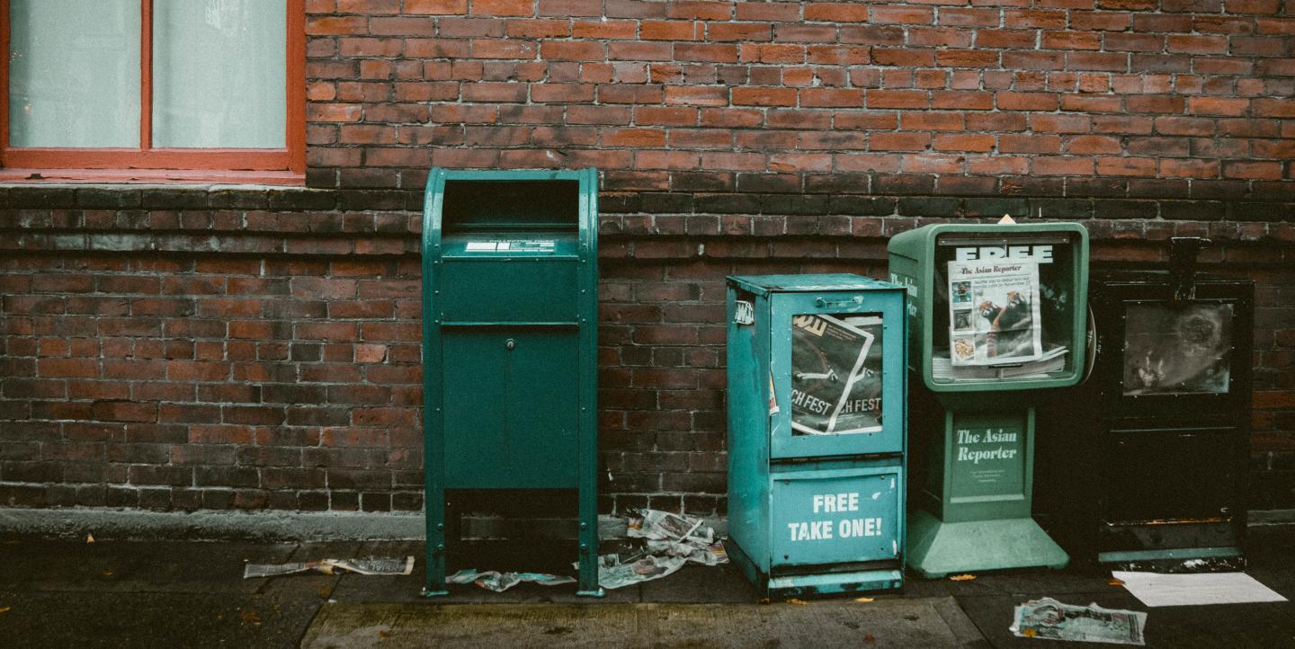 Three newspaper stands, one reads "free, take one!"