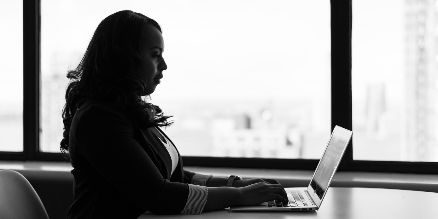 Une femme tape sur son ordinateur, contre-jour
