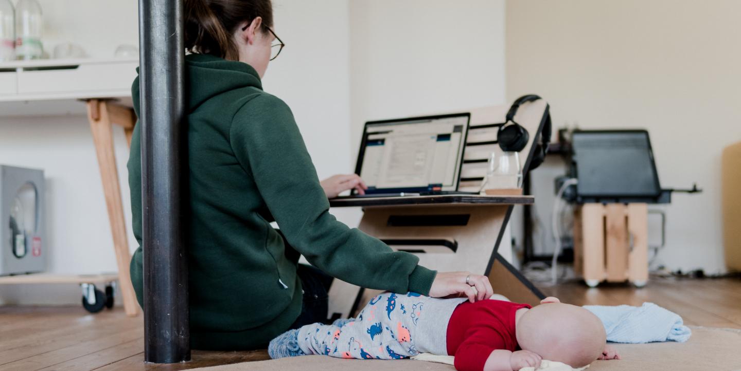 Mulher com uma mão no computador e a outra sobre um bebê