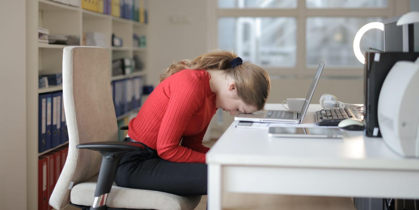 Une femme sur son bureau, la tête sur son clavier d'ordinateur