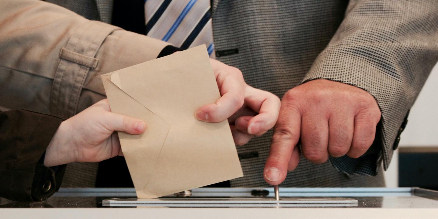 Des personnes glissent des bulletins de vote dans l'urne 