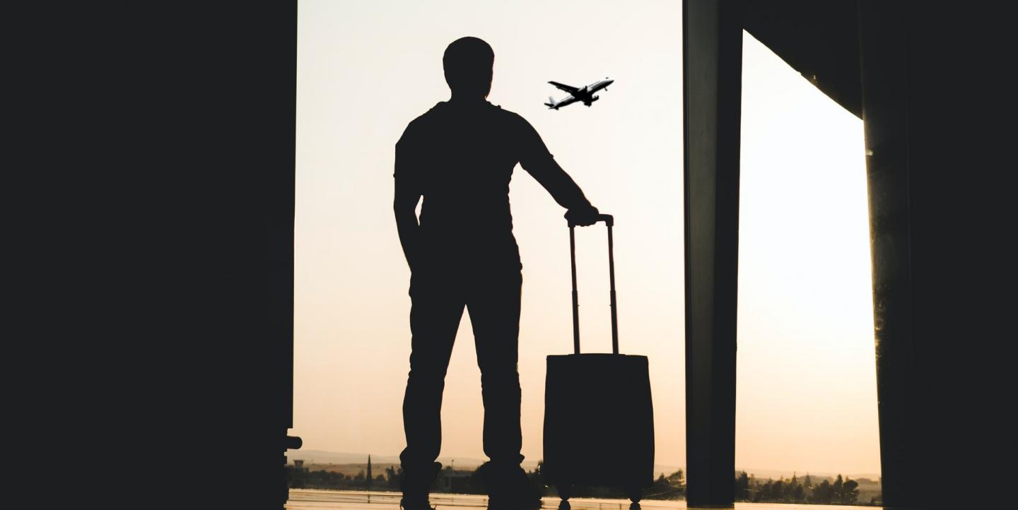 Un homme avec une valise, un avion au loin 