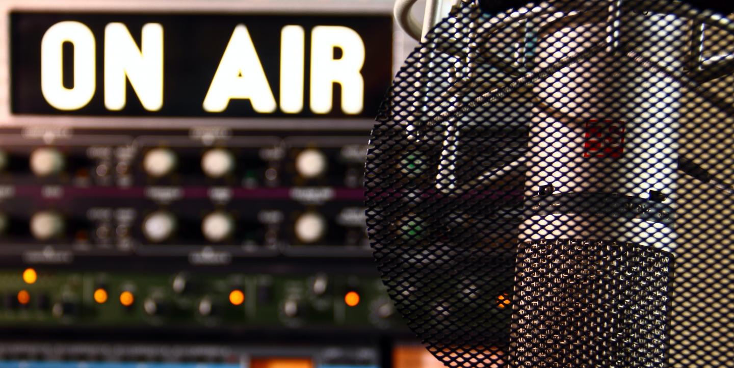 A microphone with an on air sign in the background. 