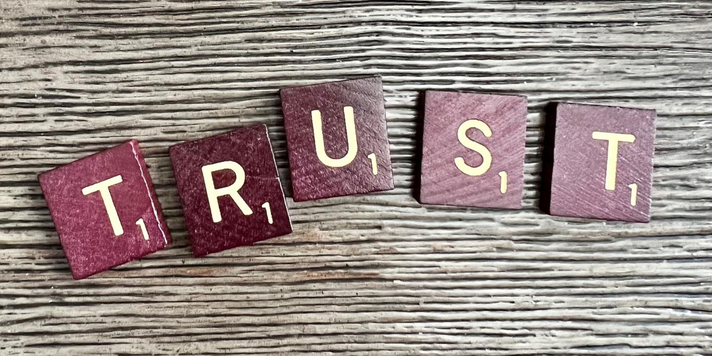 Des lettres en bois d'un jeu de scrabble, écrivent "Trust", confiance en anglais.