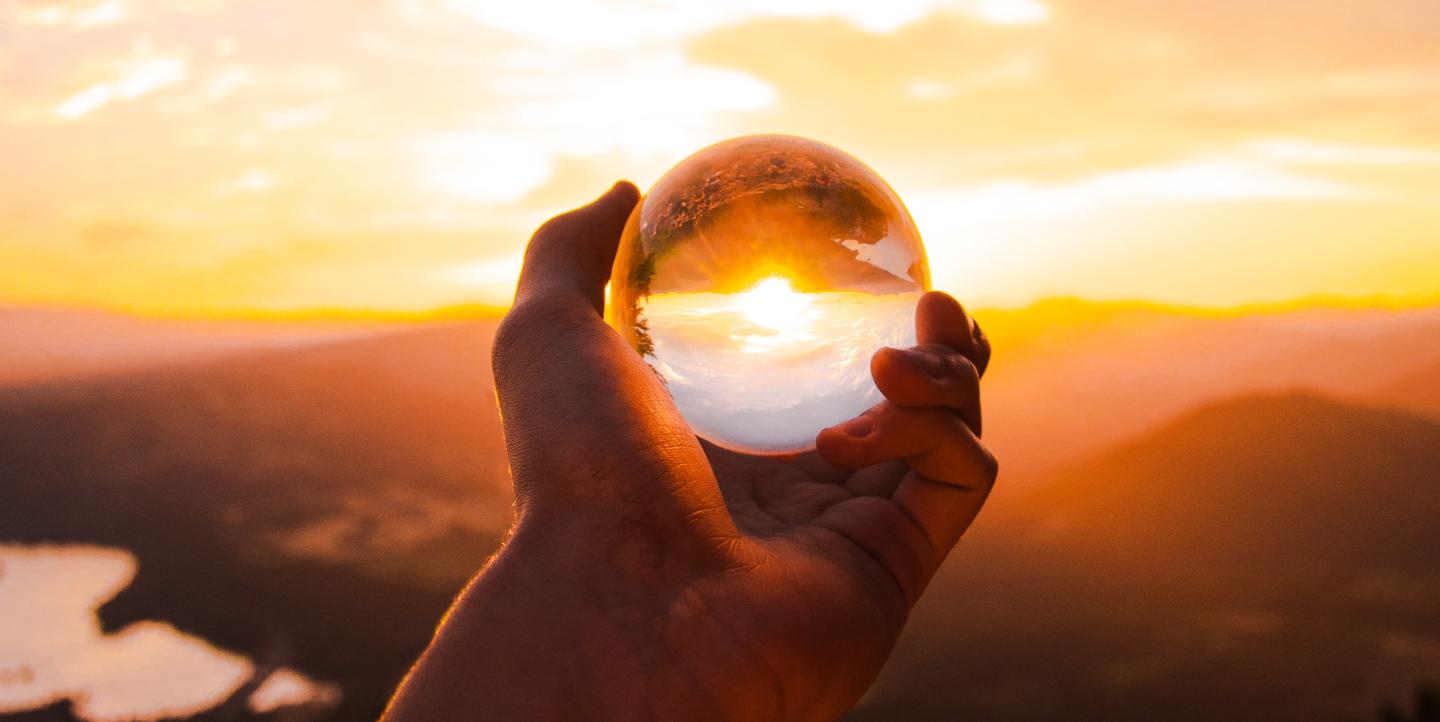 Person holding crystal ball to the sun. 