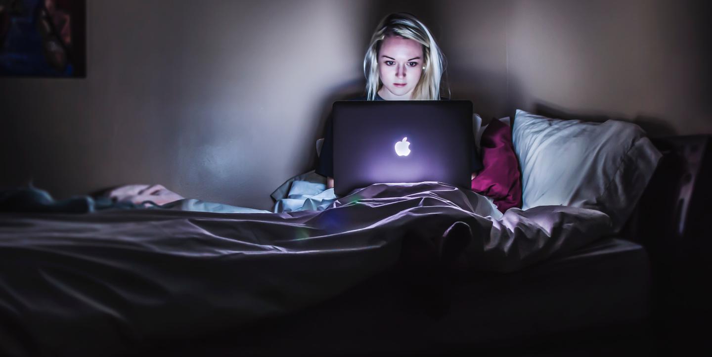 Une femme, seule, sur son ordinateur, dans la nuit 