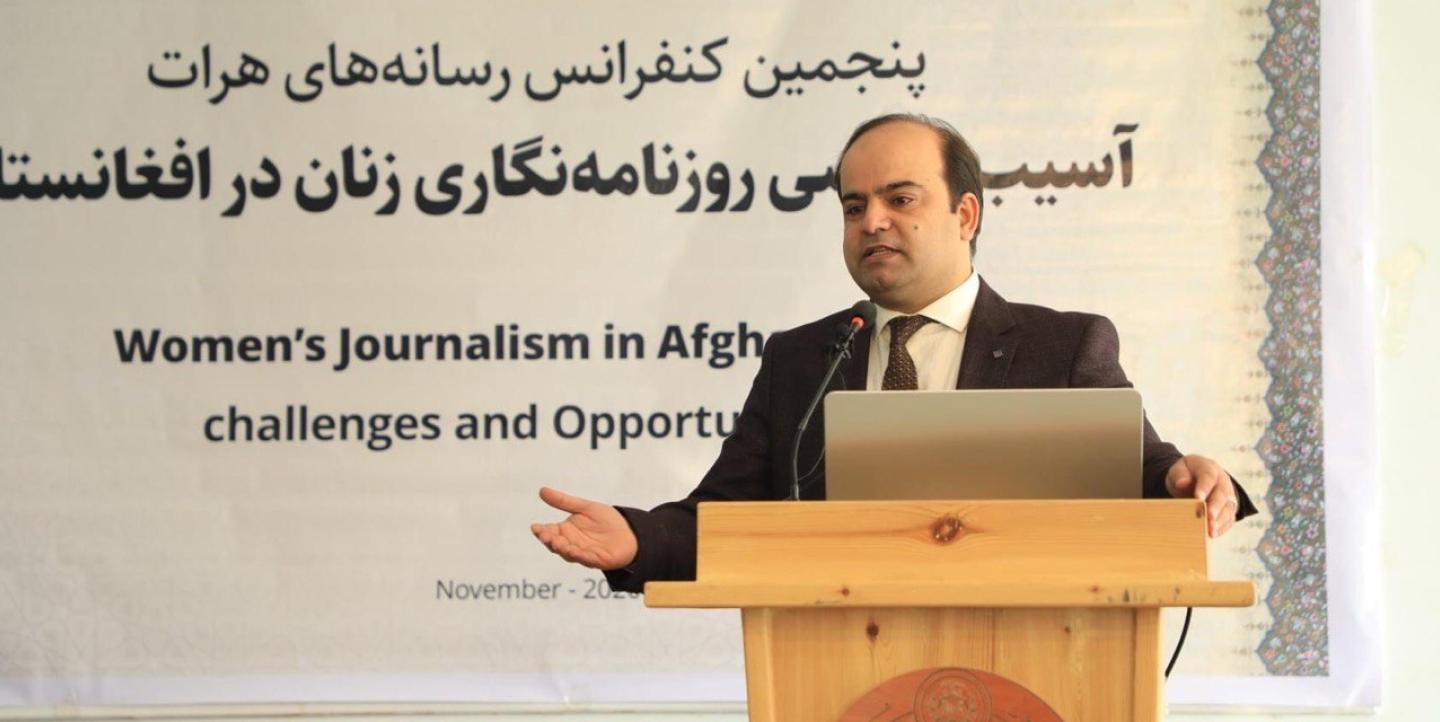 Faisal Karimi standing at a lectern. A partially obscured sign behind him said "Women's Journalism in Afghanistan: Challenges and Opportunities".