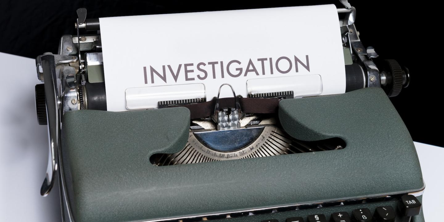 Печатная машинка с листом, на котором написано "investigation"