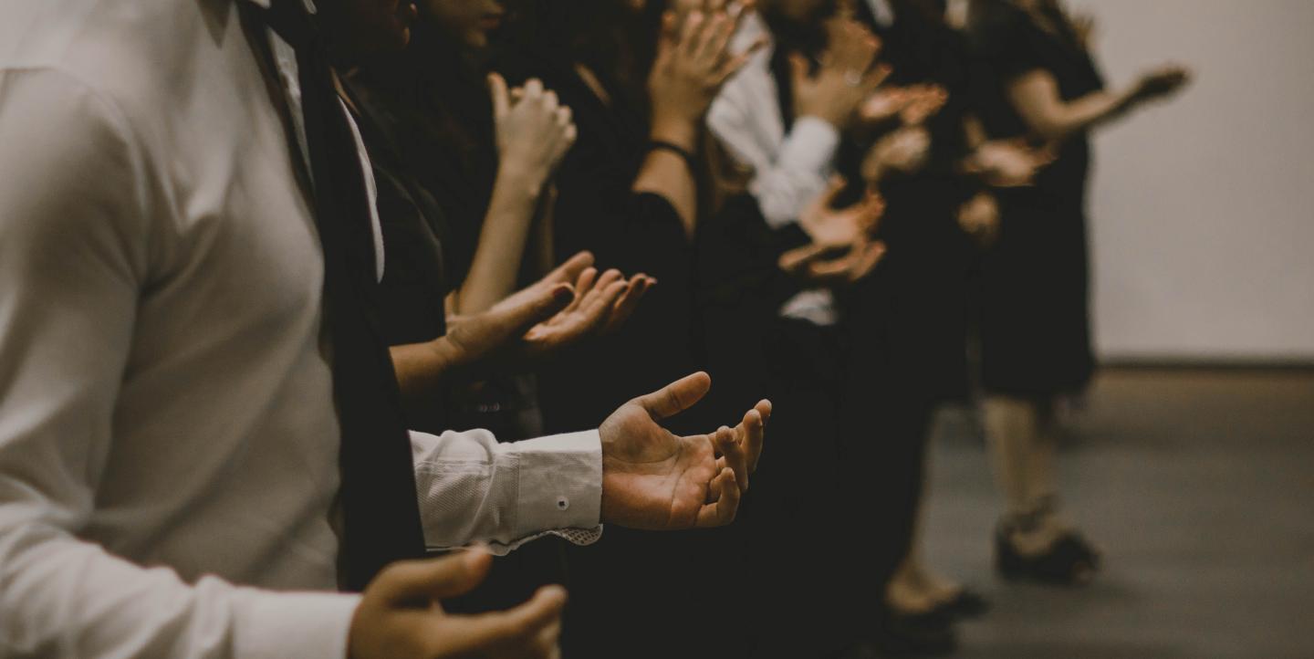 Gente rezando con las manos en alto