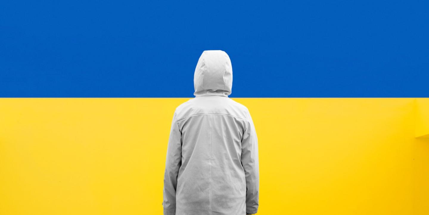 Person stands in front of Ukraine flag