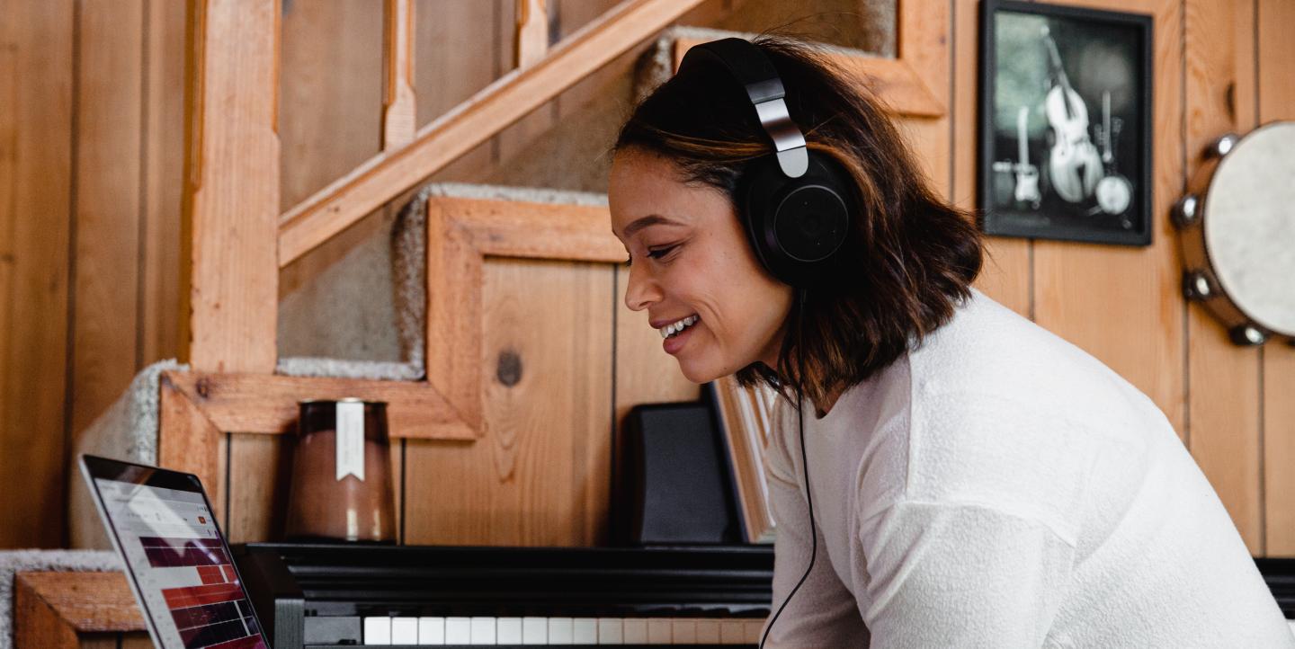 Women with headphones editing audio files on her laptop.