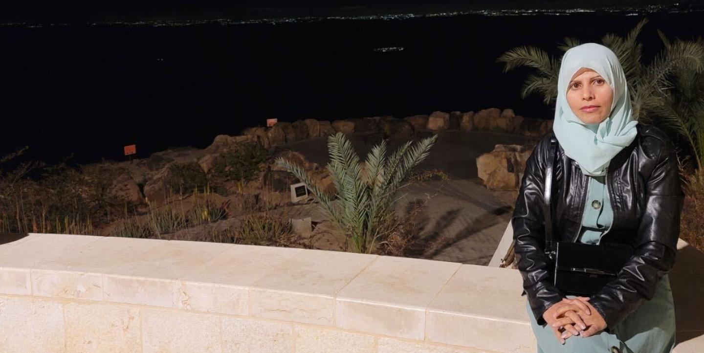 Huda Harbi assise sur un mur dans la nuit