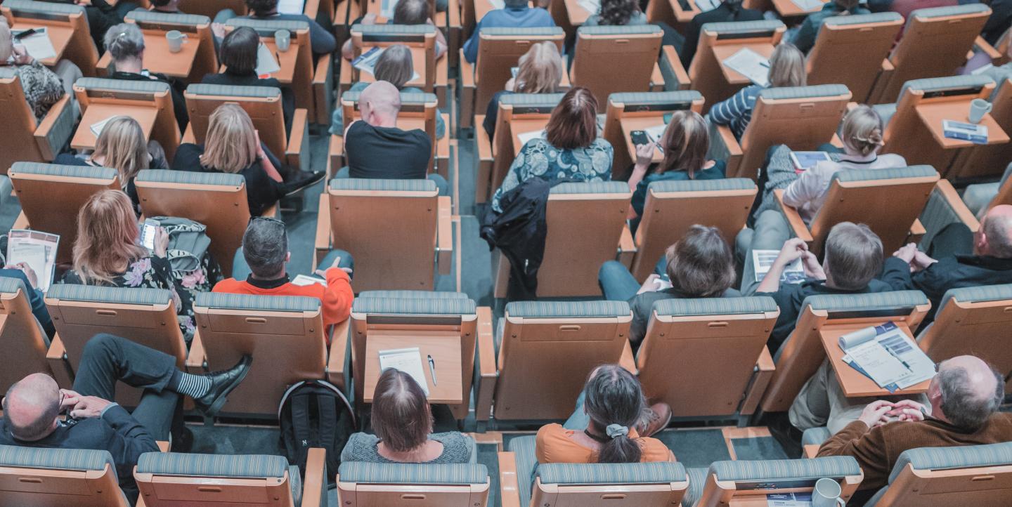 People sitting in an auditorium listening to a presentation.