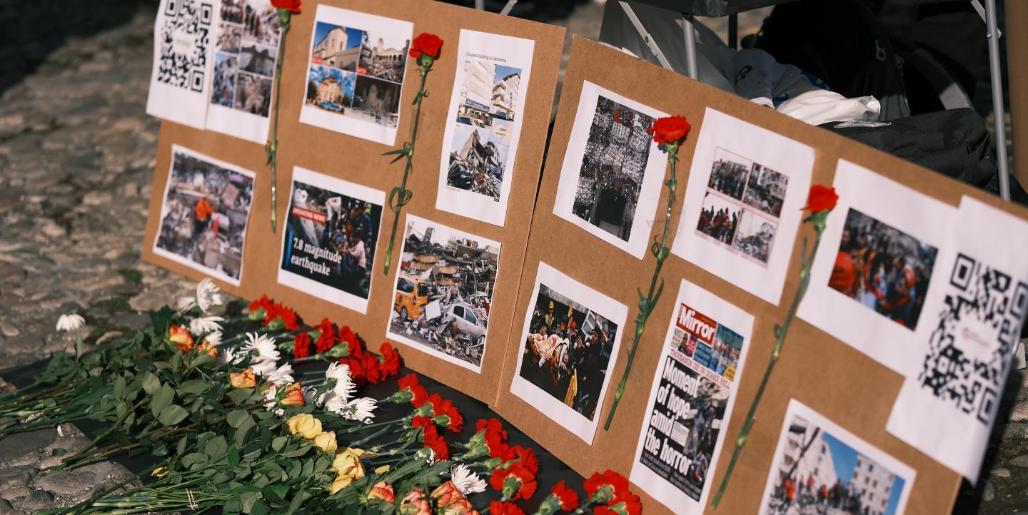 Board with flowers in front of it showing victims of Turkey earthquake