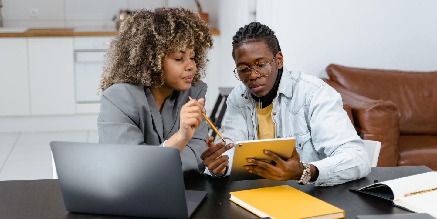 A man and a woman looking at a notebook.