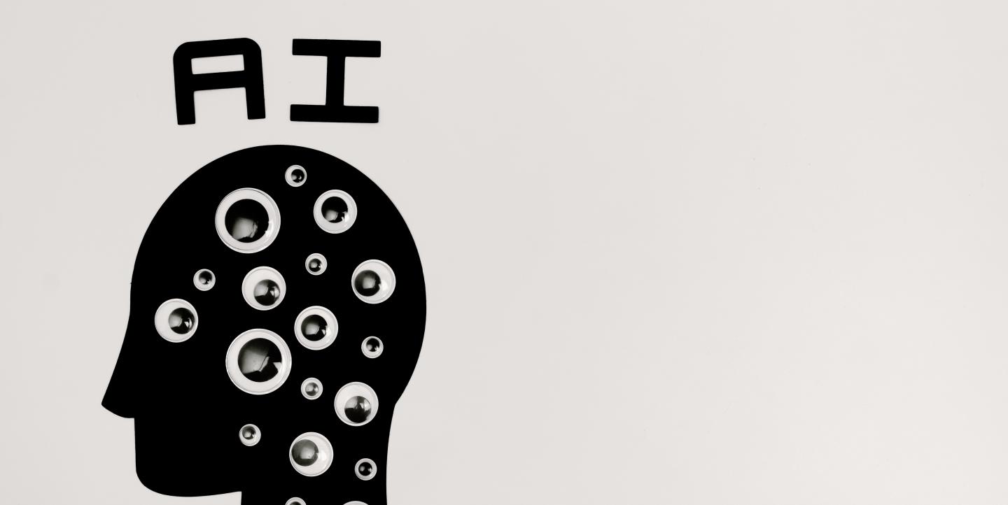 A black silhouette of a head with googly eyes on it and the letters "AI" over the head.