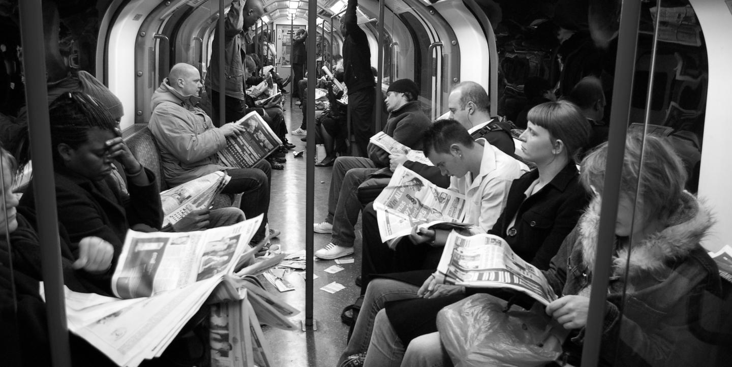 People in train reading newspapers