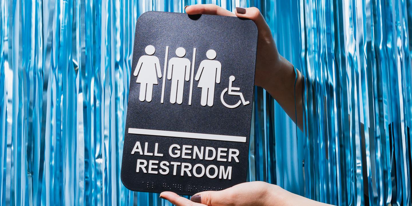 Gender inclusive restroom sign in front of a blue background