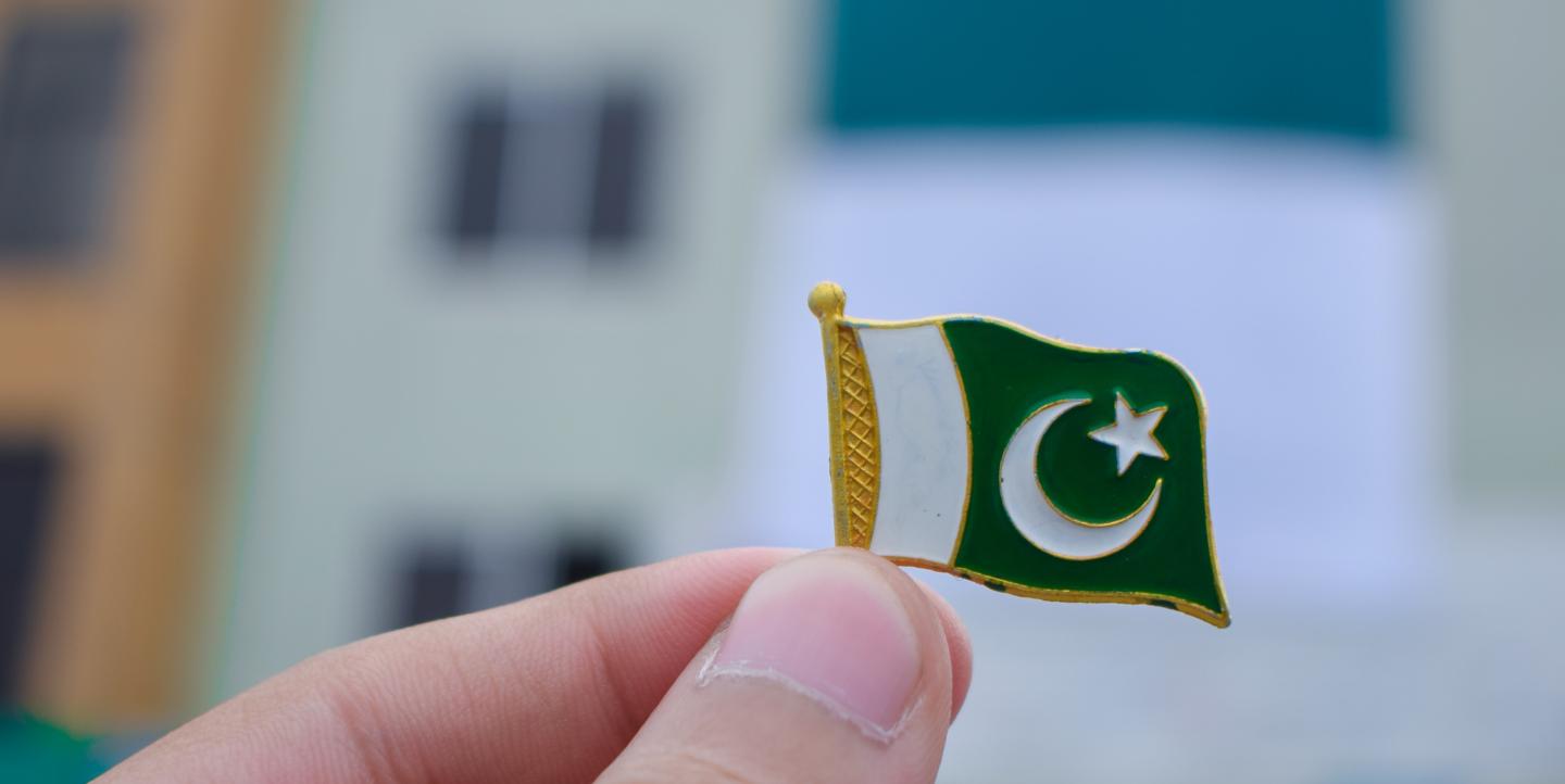 Person holding up a pin of flag of Pakistan