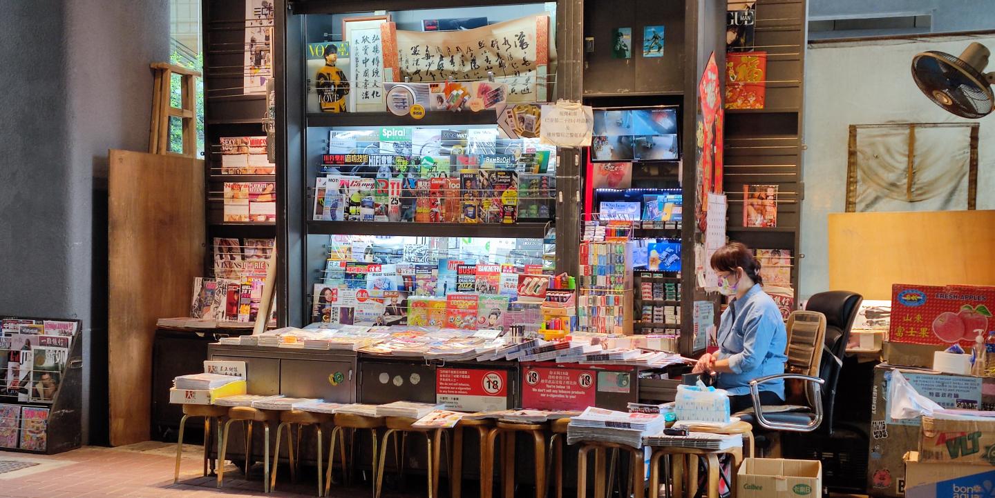 Woman in Hong Kong standing in front of a newspaper stand