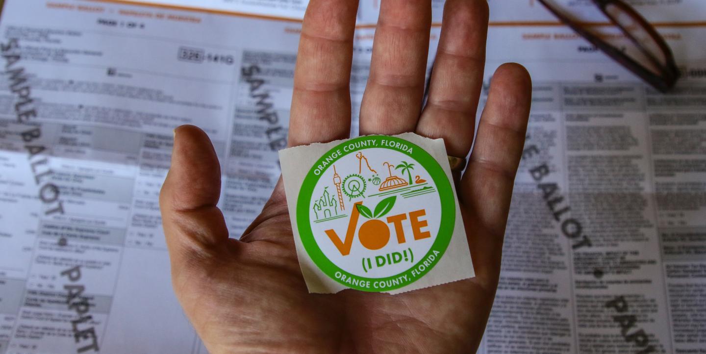Mano sosteniendo el sticker "I Voted"