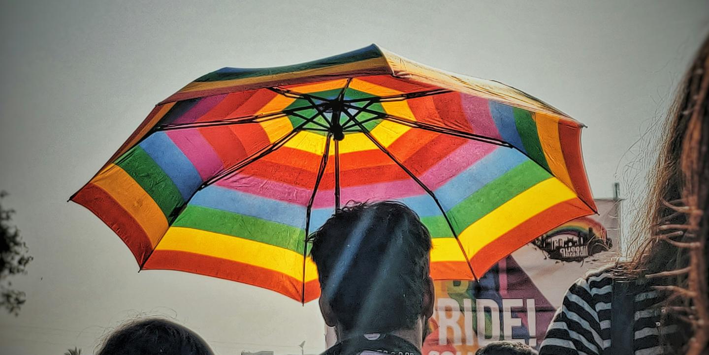 Hombre con paraguas arco iris en una protesta