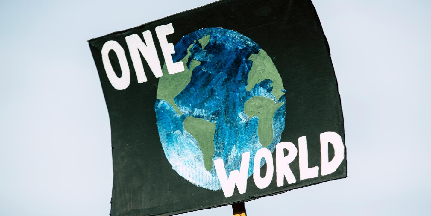 Une pancarte avec une planète Terre et le texte One World