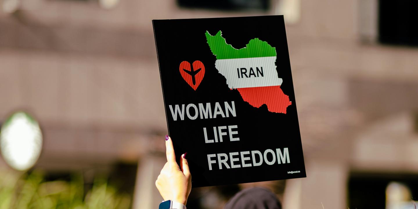 Mujer sosteniendo un cartel que dice "Irán. Mujer, vida, libertad".