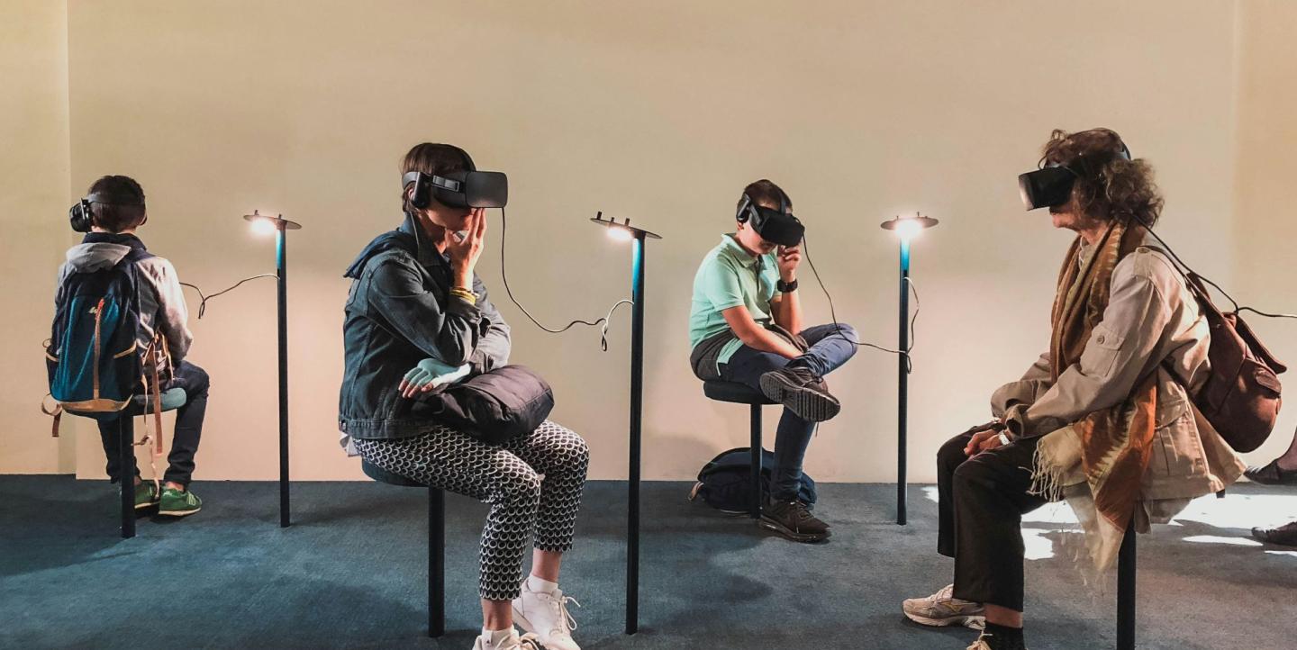 Four people sitting in a room with VR headsets on