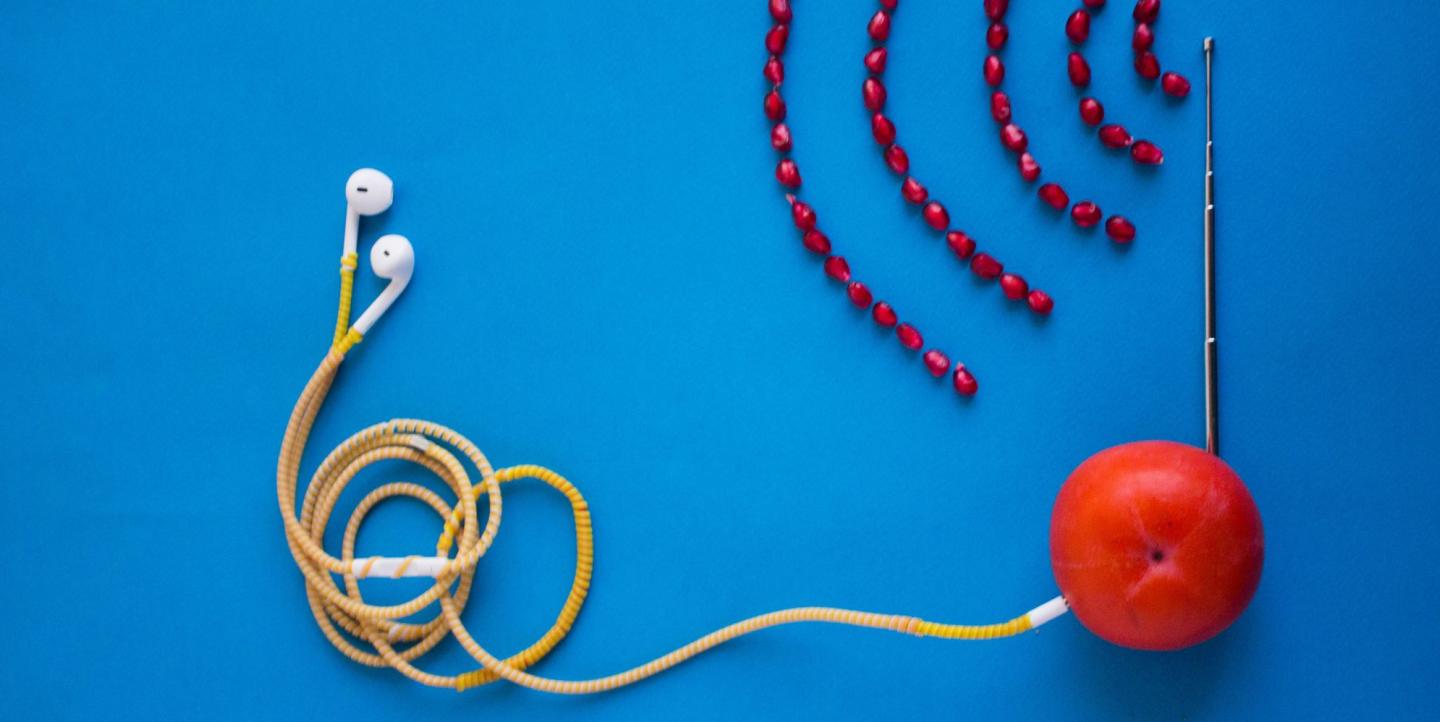 Artistic depiction of a podcast, with headphones plugged into an orange and radio waves made of beans