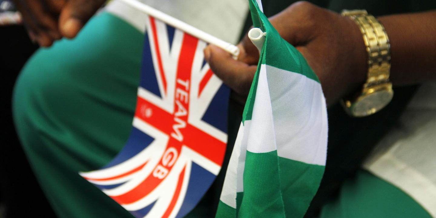 Hombre sosteniendo una bandera del Reino Unido y otra de Nigeria