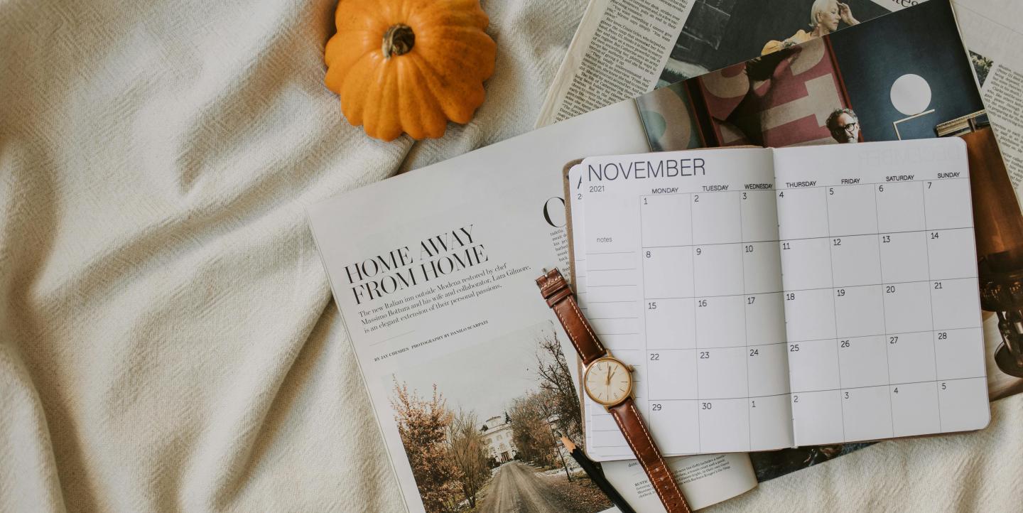 November planer with a watch, magazines, and pumpkin surrounding it.