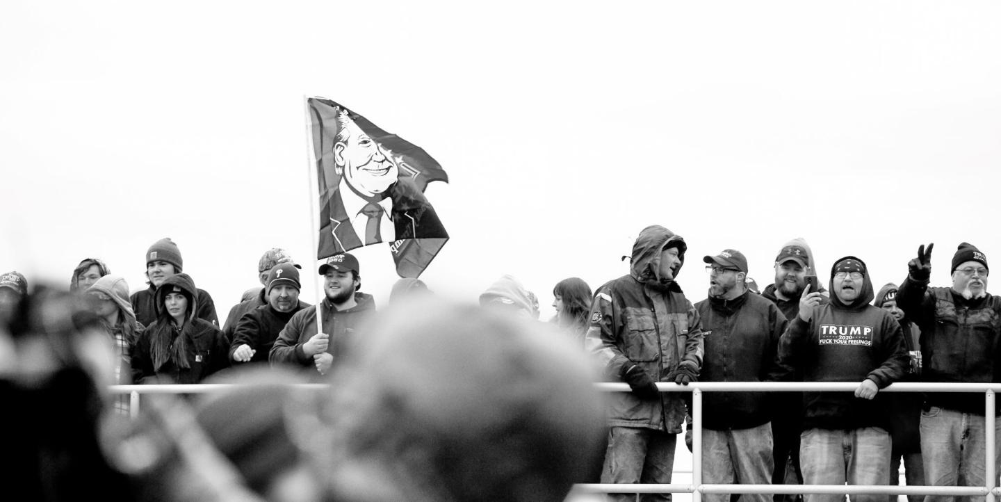 Manifestantes ondean una bandera con la cara de Trump