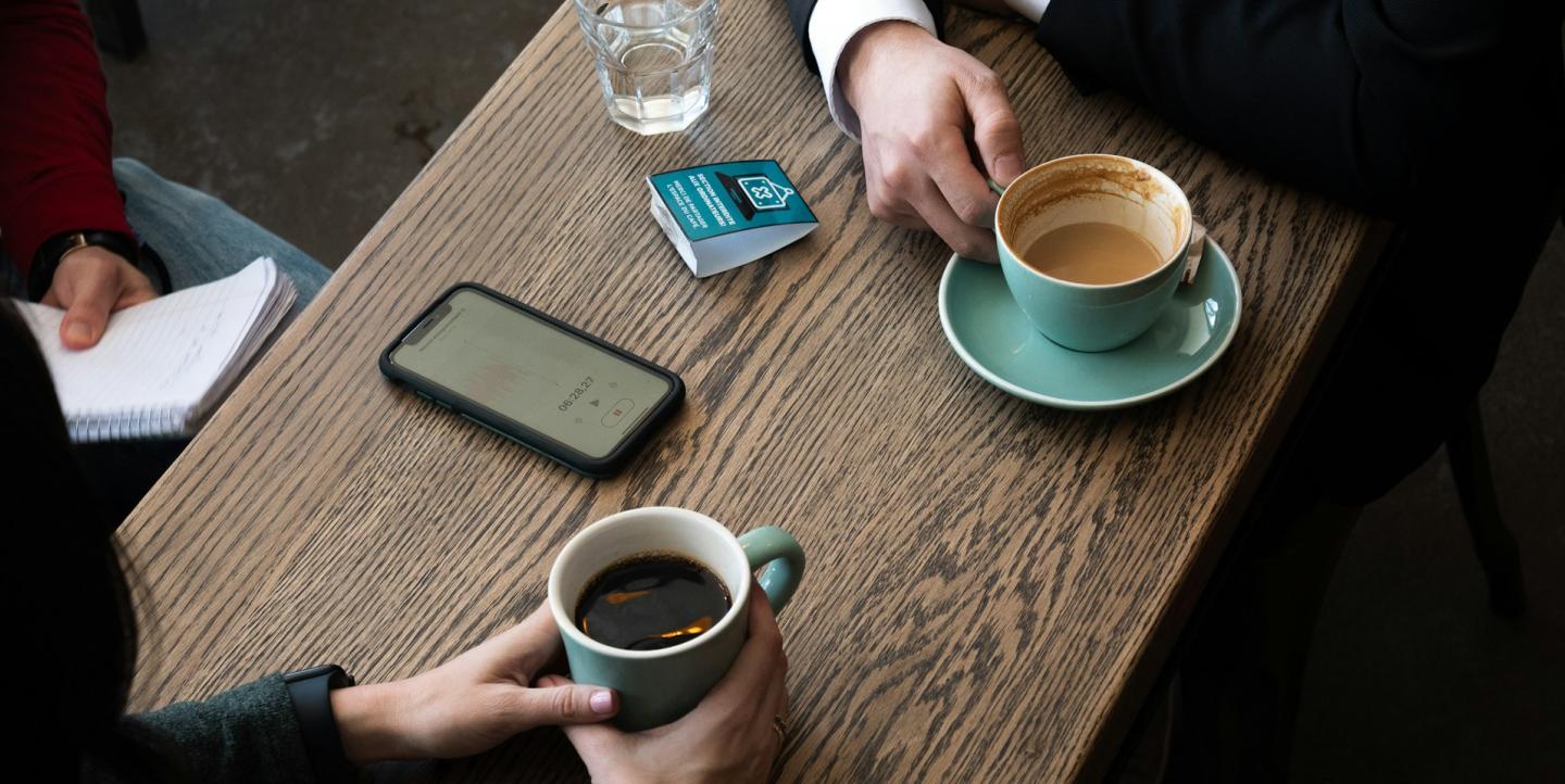 a couple of people sitting at a table with a cup of coffee