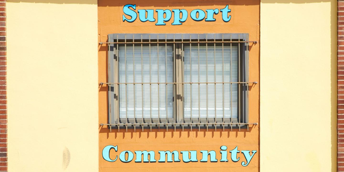 Edificio con las palabras "support community" ("apoya a la comunidad") pintadas alrededor una ventana