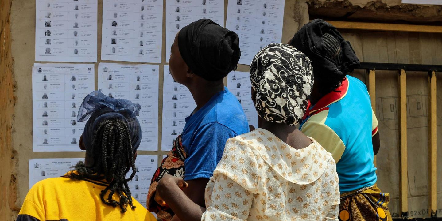 Quatre femmes au Nigéria lisant une liste électorale sur un mur