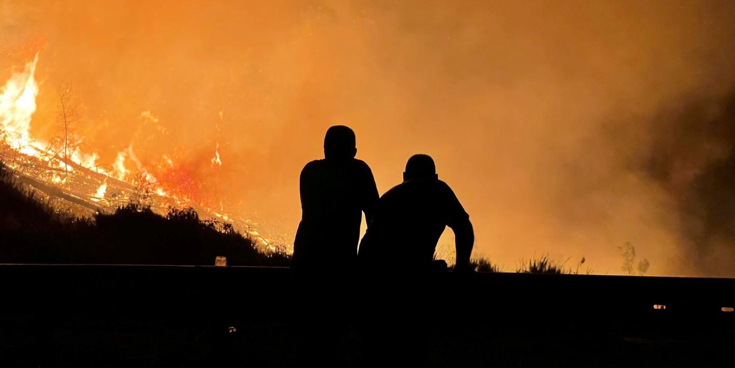 Two man silhouetted by a fire