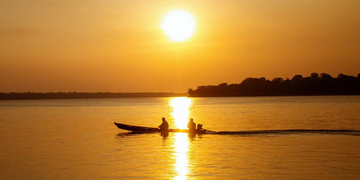 Deux hommes sur un bateau au crépuscule en Amazonie