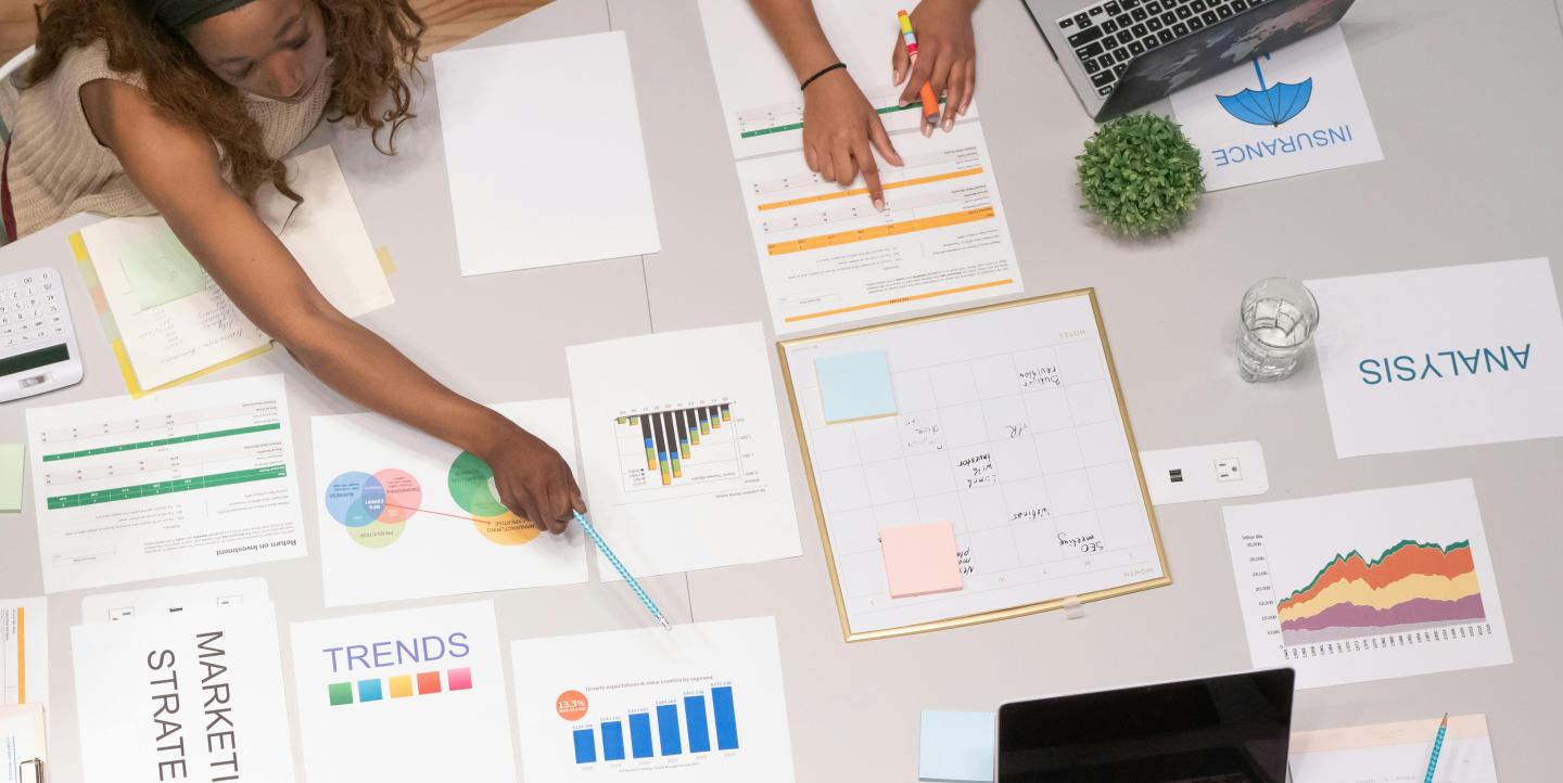 Mujer señala un gráfico de barras en una reunión laboral