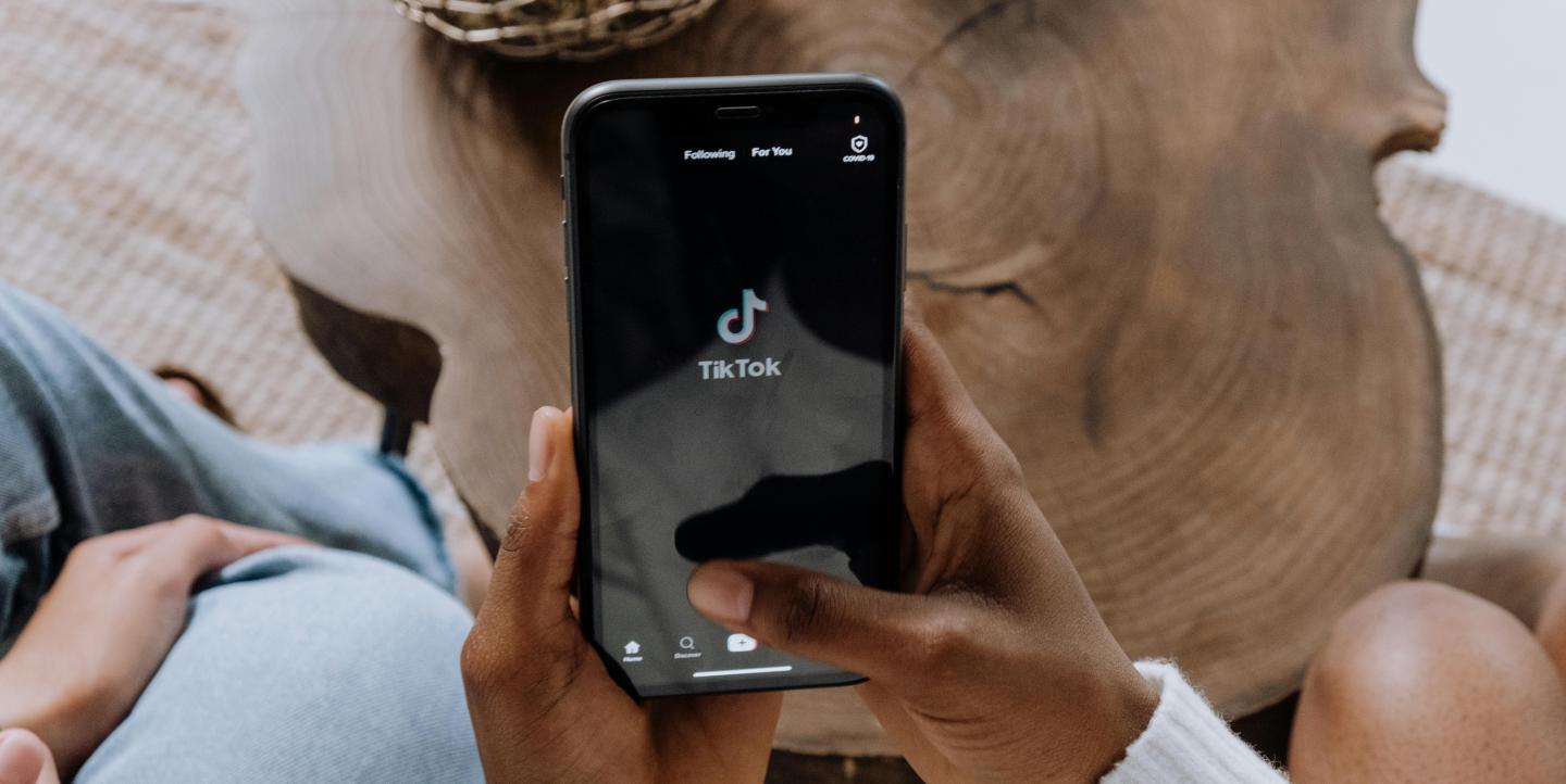 Someone holding their phone and the TikTok logo on the screen.