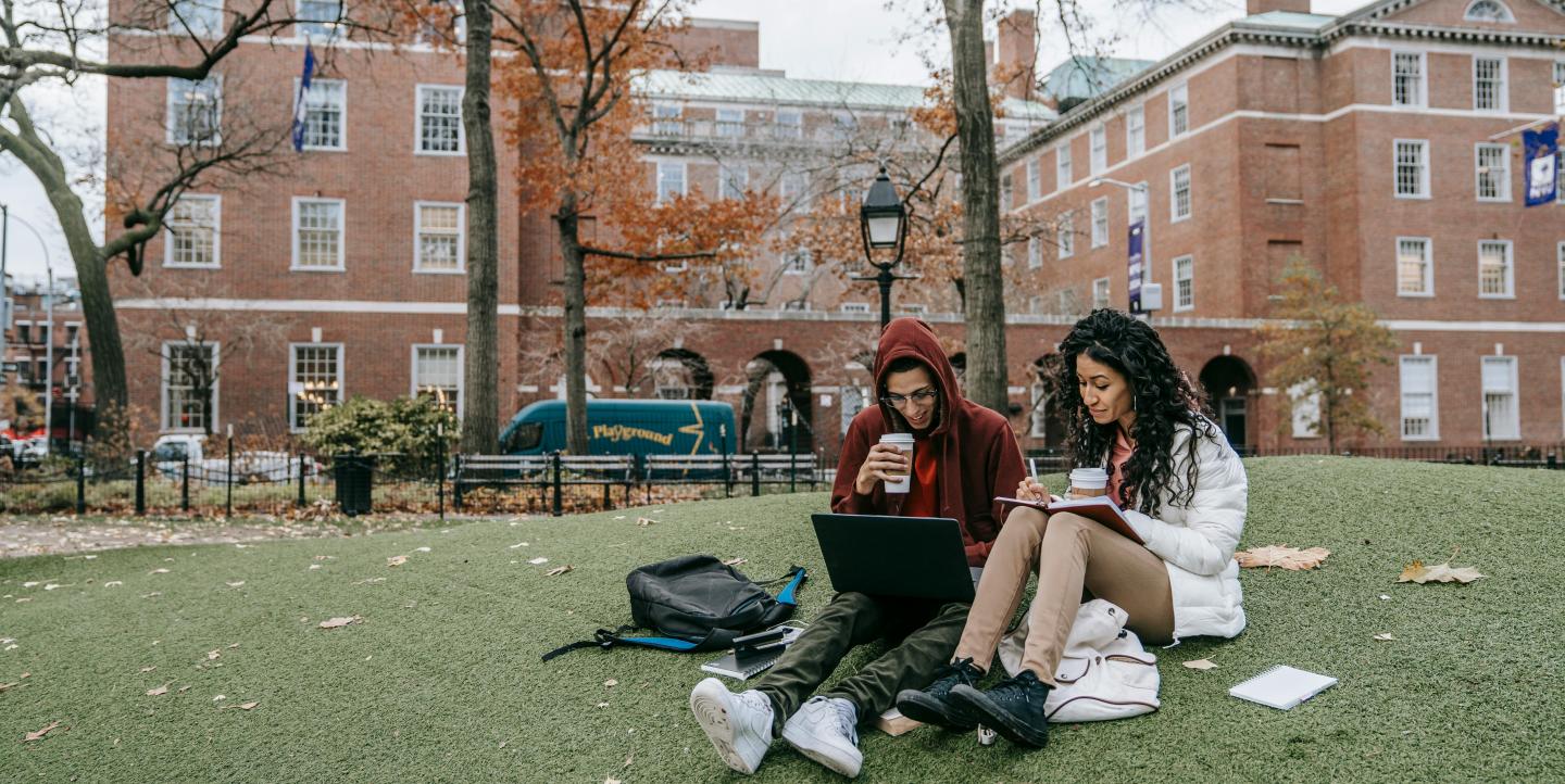 Man and woman studying outside on a college campus.